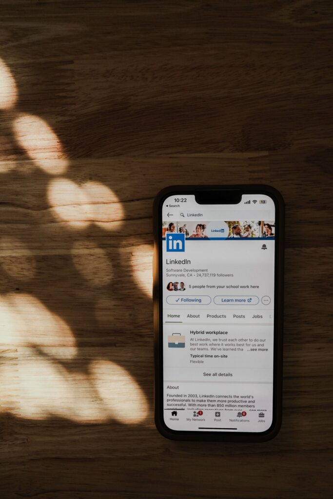 Handy mit geöffnetem LinkedIn Feed auf einem Tisch